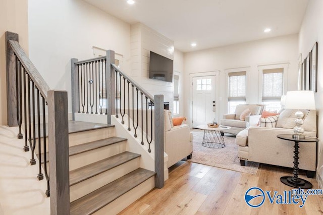 living room featuring recessed lighting, wood-type flooring, and stairway