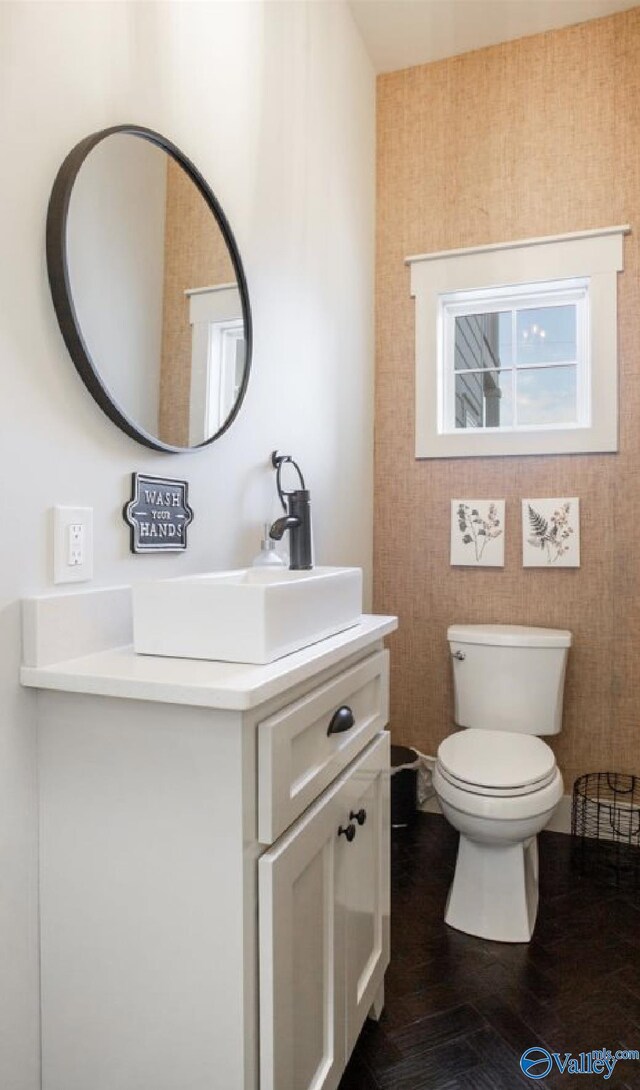 half bathroom featuring wood finished floors, vanity, and toilet