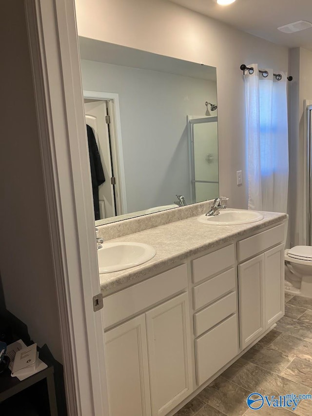 bathroom featuring toilet and dual bowl vanity