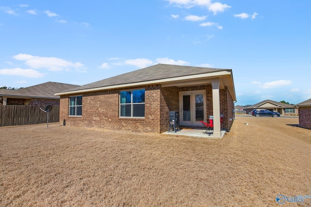 back of property featuring a yard, brick siding, fence, and a shingled roof