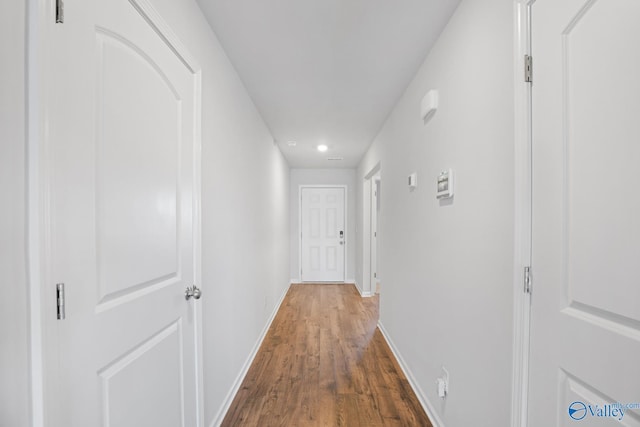 hallway featuring dark wood finished floors and baseboards