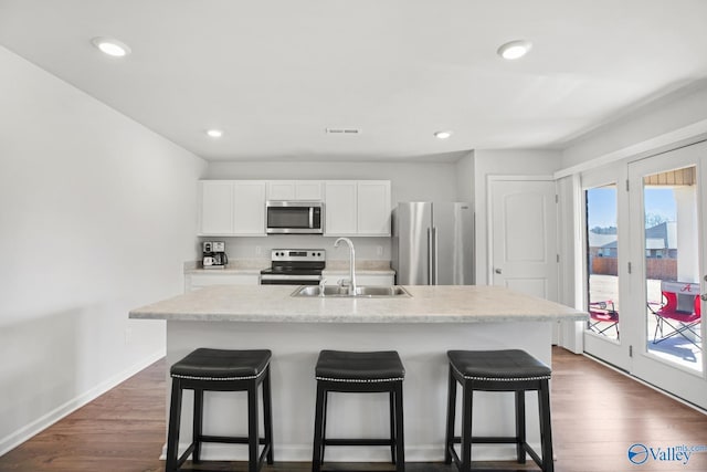 kitchen featuring stainless steel appliances, visible vents, a sink, and a kitchen bar