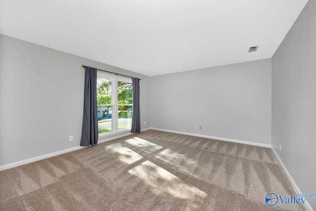 unfurnished room with carpet flooring, visible vents, and baseboards