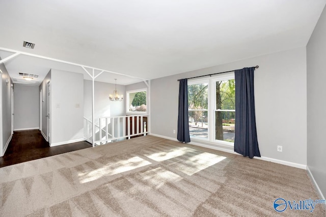 empty room featuring visible vents, baseboards, carpet, and a notable chandelier