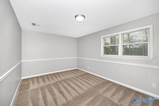 carpeted spare room featuring a textured ceiling, baseboards, and visible vents