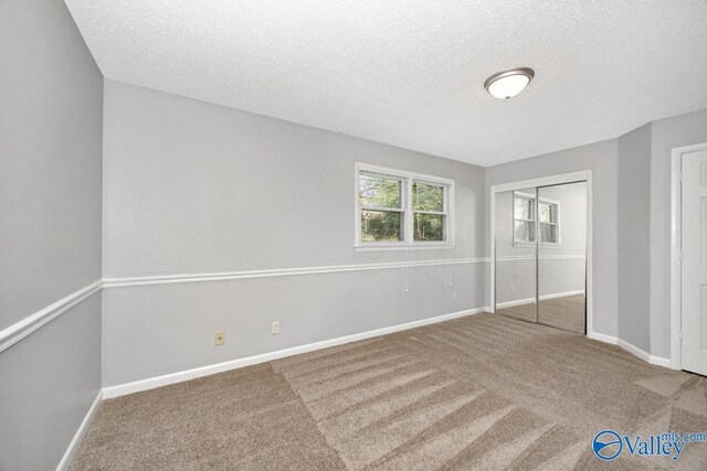 unfurnished bedroom with baseboards, carpet flooring, and a textured ceiling