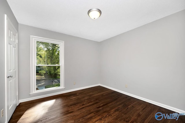 empty room with baseboards and dark wood finished floors