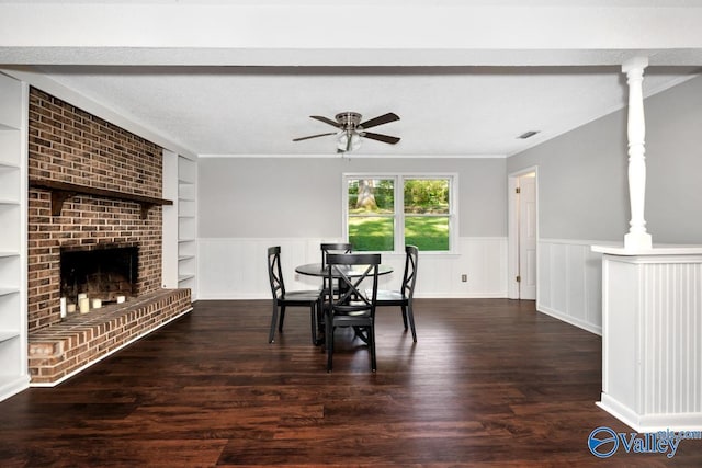 dining area featuring built in shelves, ornamental molding, a ceiling fan, wood finished floors, and a wainscoted wall