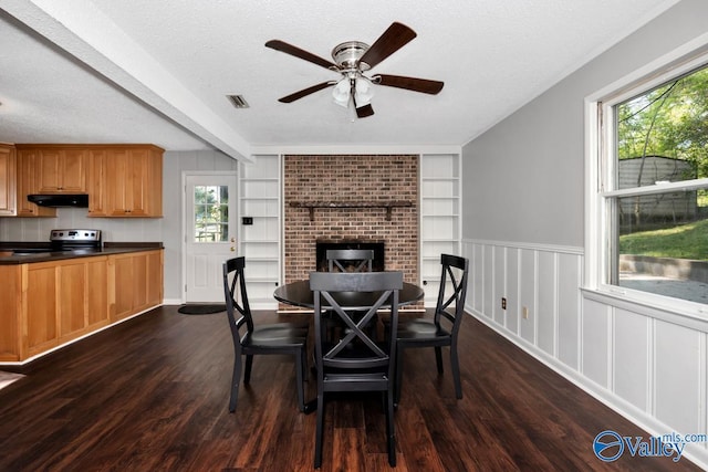 dining room with ceiling fan, a textured ceiling, visible vents, built in shelves, and dark wood-style floors