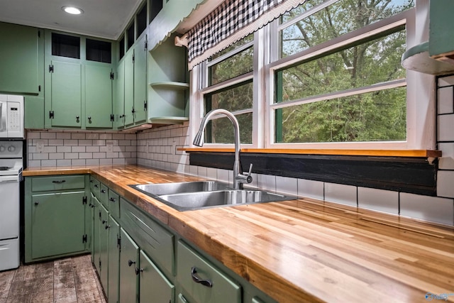 kitchen with wood counters, white appliances, green cabinets, sink, and decorative backsplash