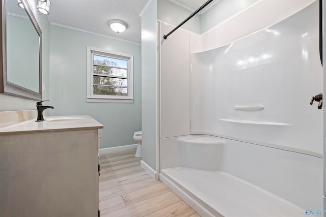 bathroom featuring ornamental molding, vanity, a shower, wood-type flooring, and toilet