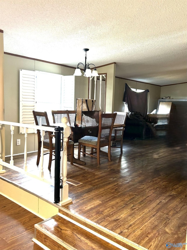 dining area with a notable chandelier, a textured ceiling, and wood finished floors