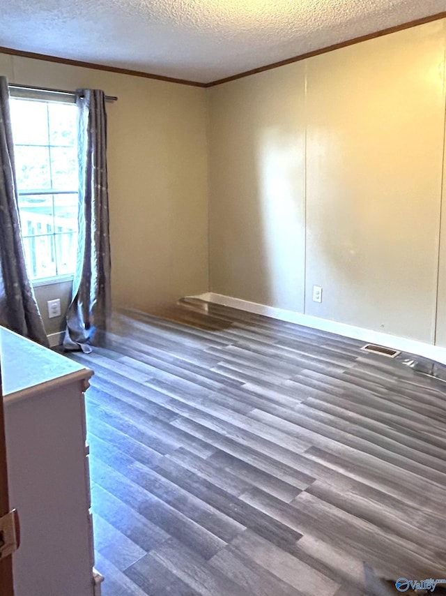 unfurnished bedroom with wood finished floors, baseboards, visible vents, a textured ceiling, and crown molding