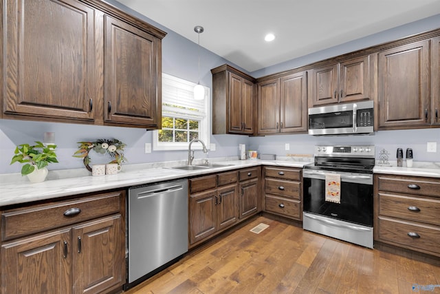 kitchen featuring stainless steel appliances, sink, decorative light fixtures, and dark hardwood / wood-style flooring