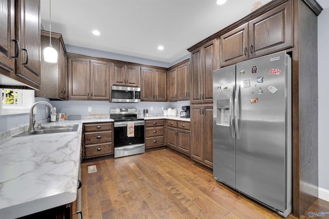 kitchen featuring sink, dark brown cabinets, light hardwood / wood-style floors, and stainless steel appliances