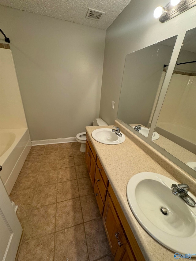 full bathroom with tub / shower combination, vanity, tile patterned flooring, toilet, and a textured ceiling