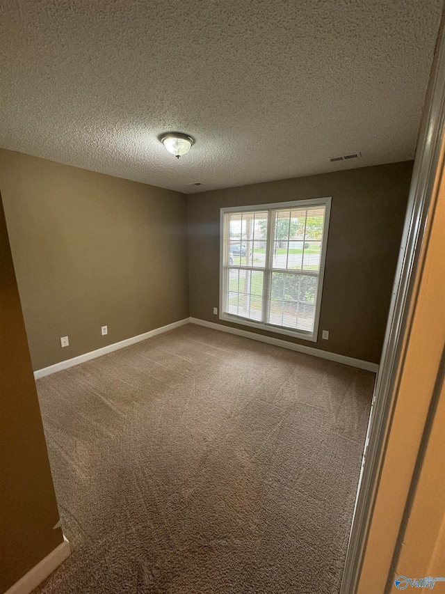 spare room with a textured ceiling and carpet