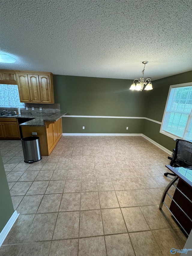 kitchen with pendant lighting, a notable chandelier, light tile patterned floors, and a textured ceiling