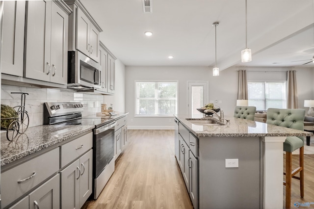 16821 Demi Dr, Athens, AL 35613 - kitchen with appliances with stainless steel finishes, a sink, gray cabinets, light wood-style floors, and a kitchen breakfast bar