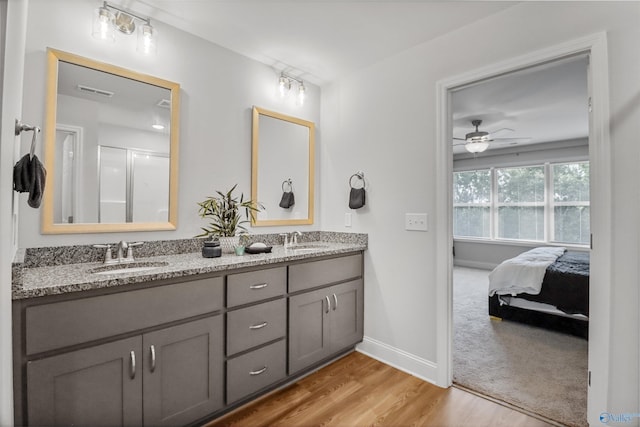 16821 Demi Dr, Athens, AL 35613 - ensuite bathroom featuring double vanity, wood finished floors, ceiling fan, a shower with door, and baseboards