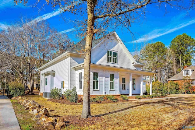 view of front facade featuring a front yard, covered porch, and central air condition unit