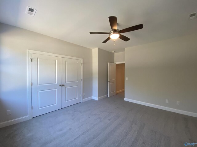 unfurnished bedroom with ceiling fan, a closet, and dark colored carpet