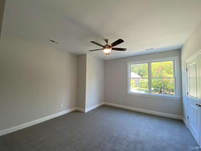 unfurnished room with ceiling fan and dark carpet