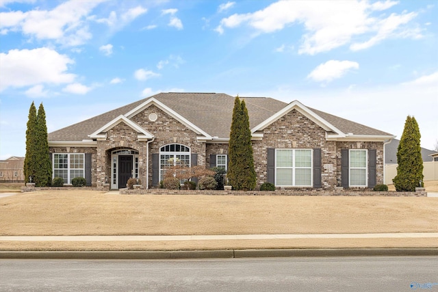 view of front facade featuring brick siding and a shingled roof