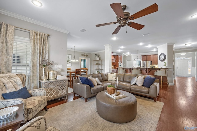 living area with ornamental molding, hardwood / wood-style floors, baseboards, ceiling fan, and ornate columns