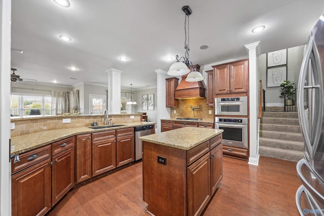 kitchen featuring a kitchen island, dark wood finished floors, appliances with stainless steel finishes, ornate columns, and a sink