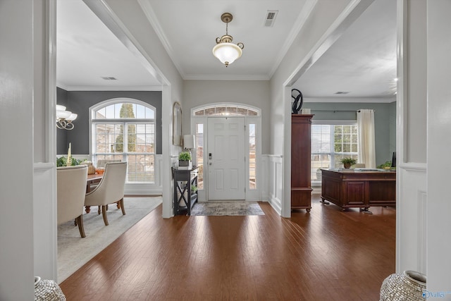 foyer entrance with visible vents, dark wood finished floors, wainscoting, and ornamental molding