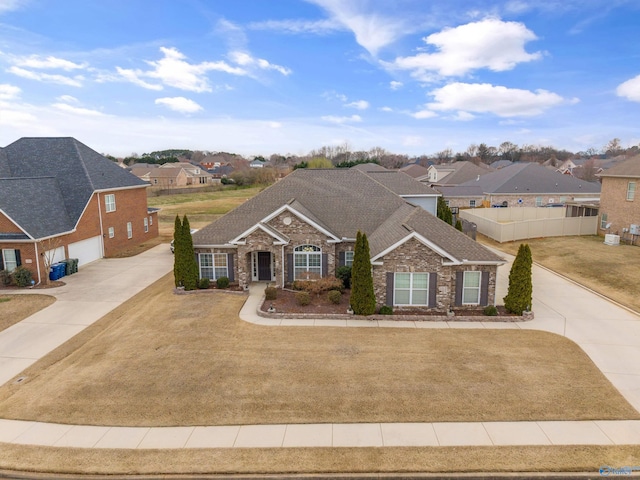 view of front of home featuring a garage, a residential view, concrete driveway, and fence