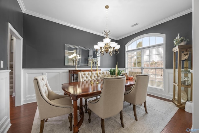 dining area featuring visible vents, a notable chandelier, wood finished floors, and wainscoting