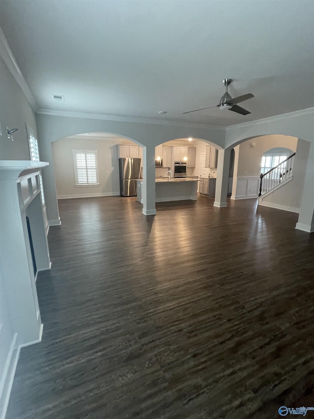 unfurnished living room featuring ceiling fan, dark wood-type flooring, and ornamental molding