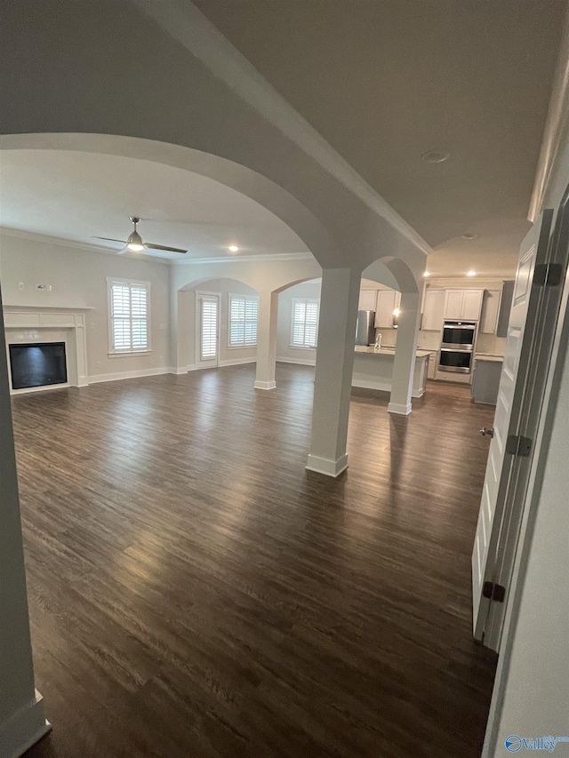 unfurnished living room with ceiling fan, dark hardwood / wood-style floors, and crown molding