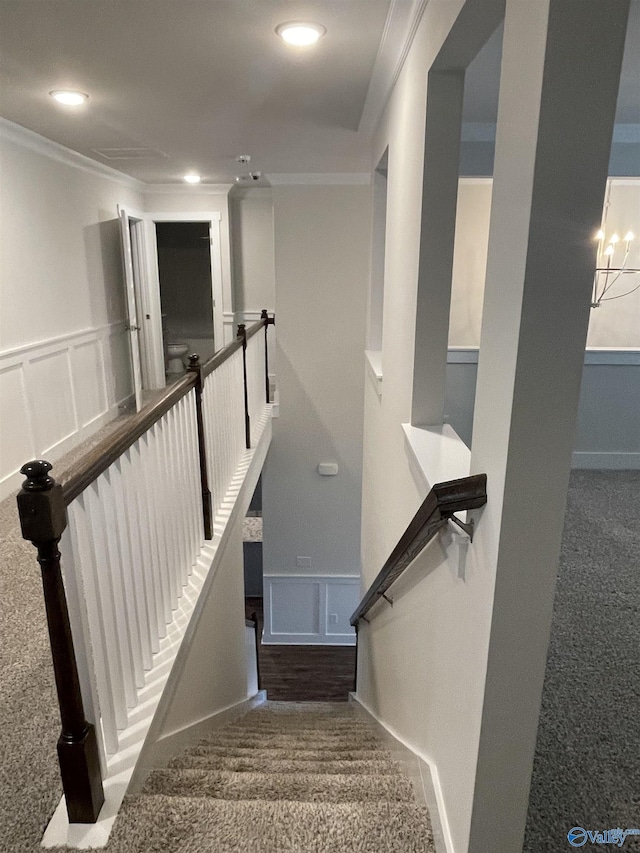 stairway with crown molding, carpet floors, and an inviting chandelier