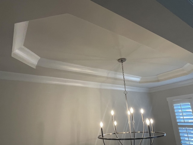 room details with a raised ceiling, an inviting chandelier, and crown molding