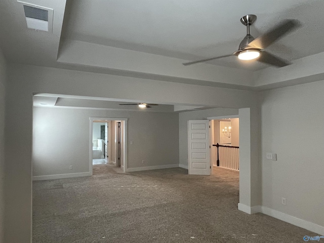 unfurnished room featuring ceiling fan with notable chandelier, carpet floors, and a tray ceiling