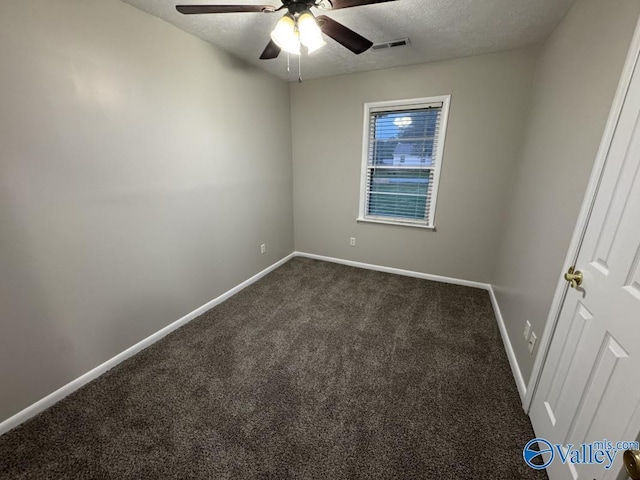 empty room featuring a textured ceiling, visible vents, dark colored carpet, a ceiling fan, and baseboards