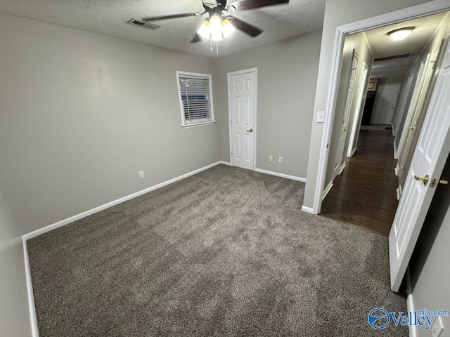 unfurnished bedroom featuring a ceiling fan, a textured ceiling, visible vents, baseboards, and dark colored carpet