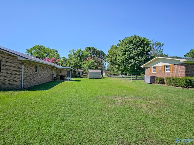 view of yard featuring central air condition unit, fence, an outdoor structure, and a shed