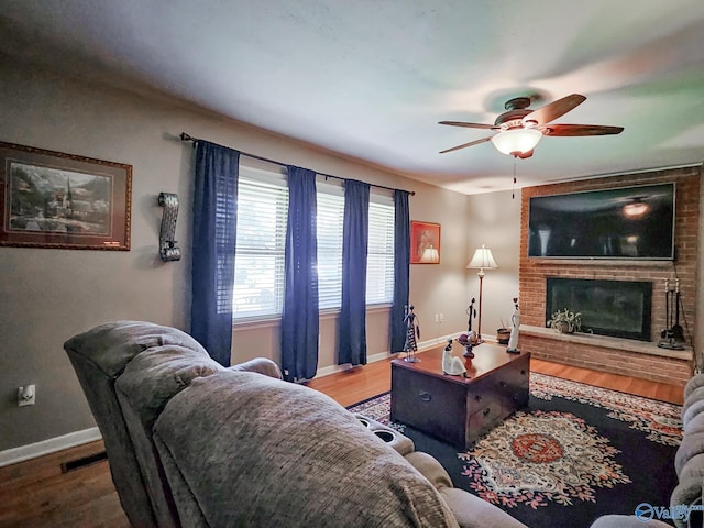 living area with visible vents, baseboards, a brick fireplace, and wood finished floors