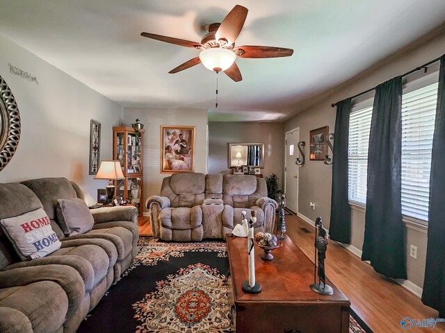 living area featuring baseboards, a ceiling fan, and wood finished floors