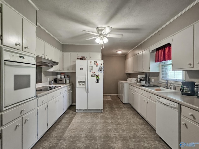 kitchen with white appliances, washing machine and clothes dryer, a sink, under cabinet range hood, and crown molding