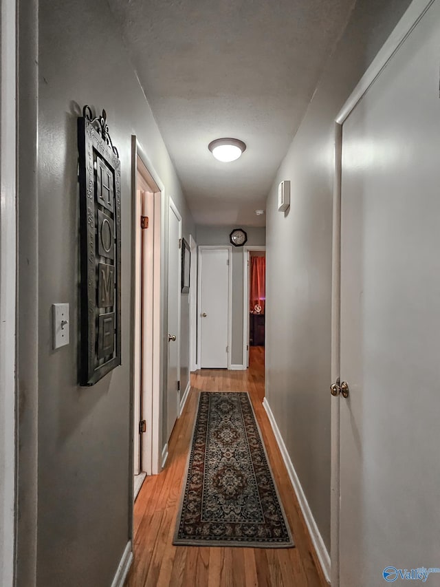 hall featuring light wood-type flooring and baseboards