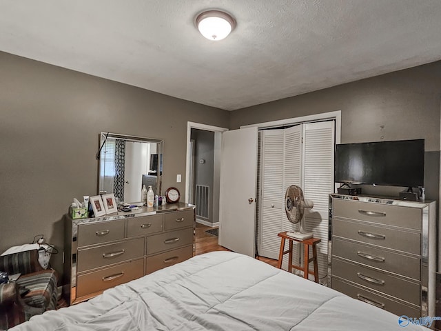 bedroom featuring a closet, dark wood finished floors, and a textured ceiling