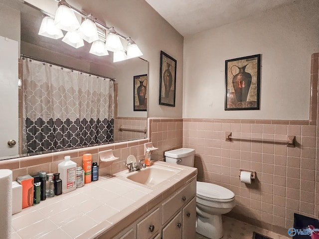 bathroom featuring toilet, a shower with shower curtain, vanity, wainscoting, and tile walls