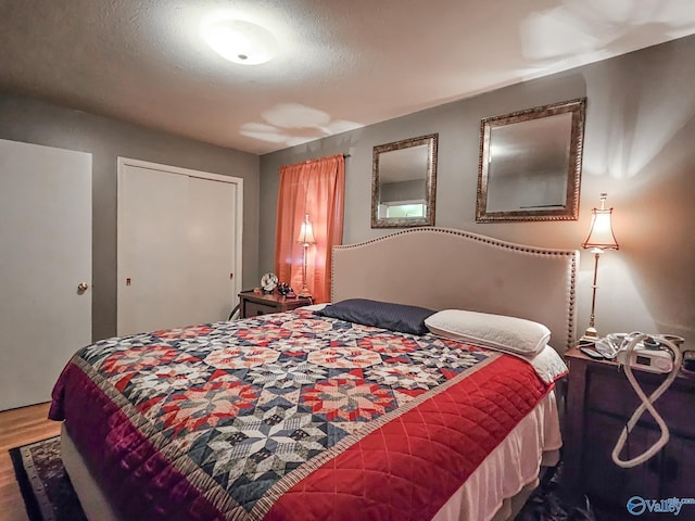 bedroom featuring a closet, a textured ceiling, and wood finished floors