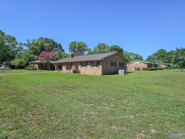 ranch-style house with a front yard, a chimney, crawl space, central air condition unit, and brick siding