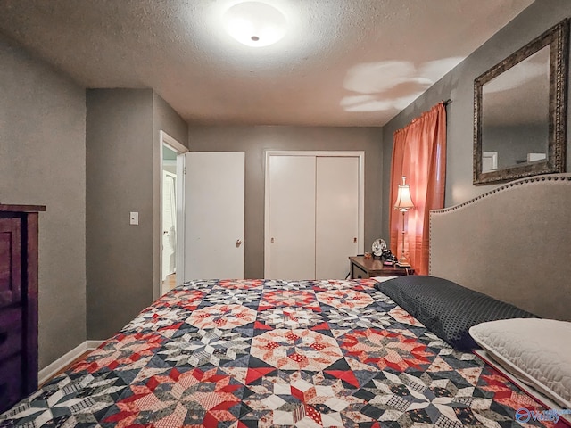 bedroom with a closet, a textured ceiling, and baseboards